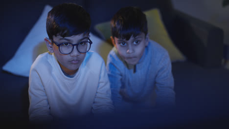 Front-View-Of-Two-Young-Boys-At-Home-Having-Fun-Playing-With-Computer-Games-Console-On-TV-Holding-Controllers-Late-At-Night-2